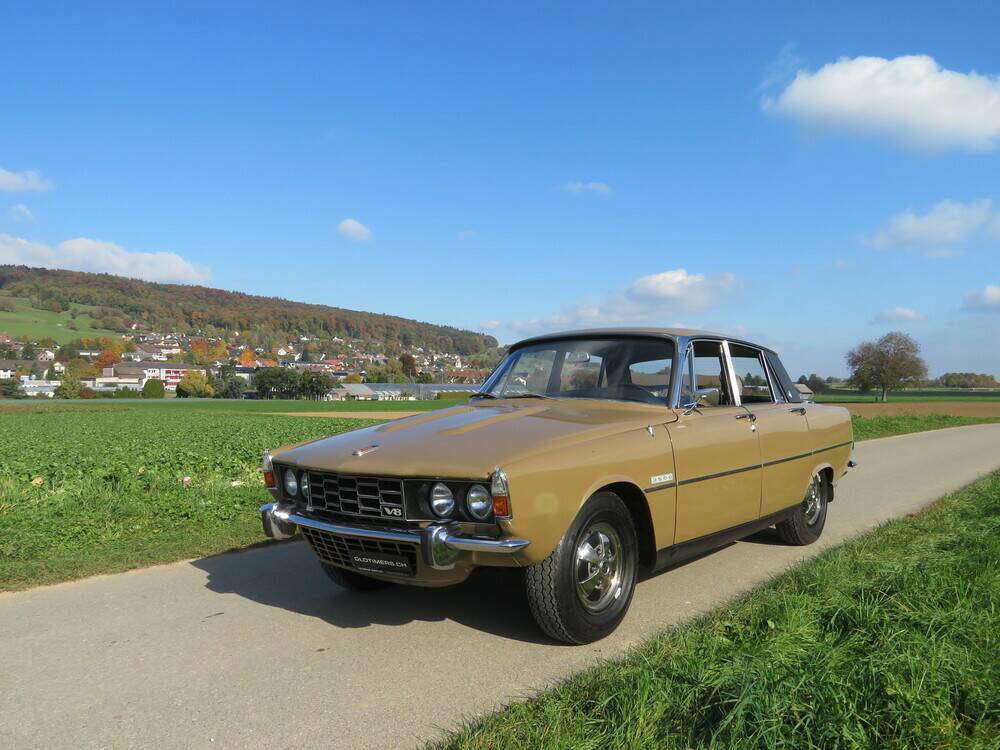 Rover P6 3500 V8 beige doré, vue de trois quarts avant, au bord d'une route de campagne